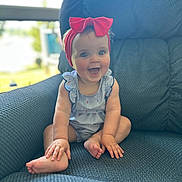 Wyatt is registered to the contest to win money with this photo: baby, child, smiling, headband, red_bow, armchair, blue_fabric, striped_outfit, happy, sitting, indoors, window, blurred_background, cute, infant, hands, feet, portrait, person, bright_eyes