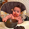 baby, high_chair, messy, food, bowl, kitchen, cute, child, face, tongue_out, expression, wallpaper, cabinet, utensil, cloth, feeding, indoor, person, happy, curious