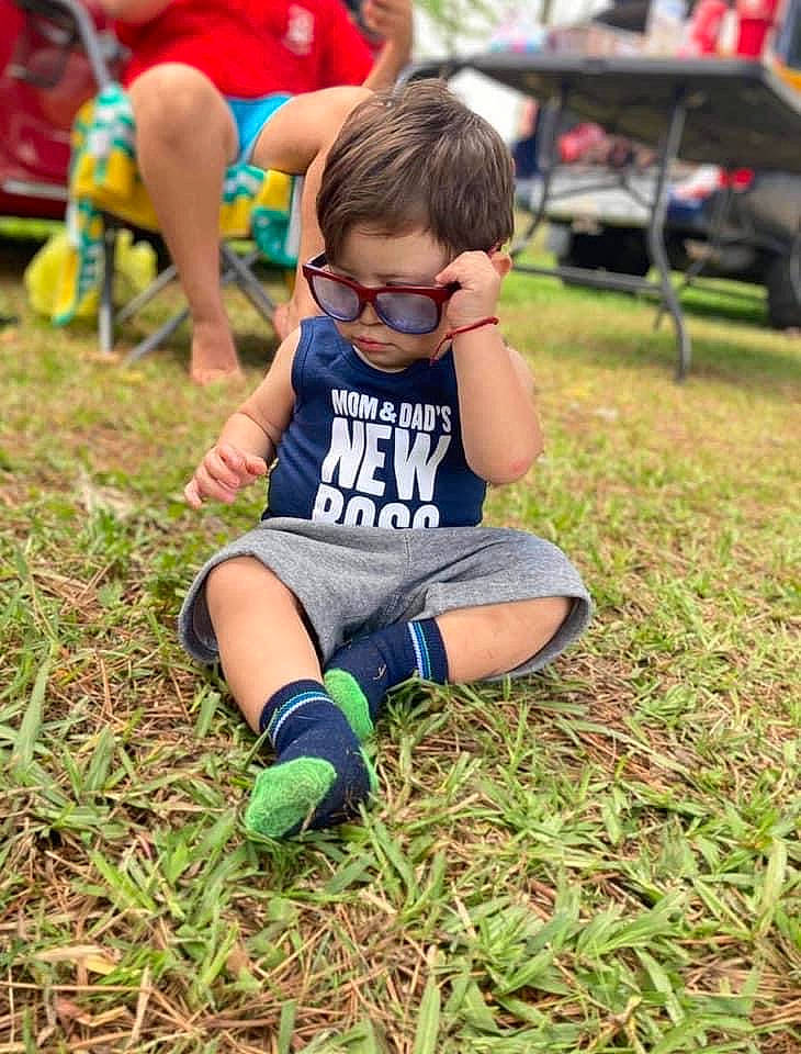 Emmanuel is registered to the contest to win money with this photo: chair, competition_event, eyewear, fun, grass, green, happy, lawn, leisure, people_in_nature, person, plant, recreation, shorts, summer, sunglasses, t_shirt, thigh, tire, toddler