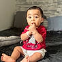 Giovanni participe au concours pour gagner de l'argent avec cette photo : baby, child, infant, toddler, sitting, bed, indoors, red_shirt, white_shorts, cute, curious, fingers_in_mouth, bracelet, home, soft_lighting, portrait, young, person, face, expression