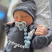 Greyson is registered to the contest to win money with this photo: baby, newborn, pacifier, hat, grey_clothing, sleeping, infant, beads, clip, soft_focus, cozy, cute, child, person, portrait, indoors, resting, blanket, hand, peaceful