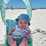 Rustyn joined the competition — help win amazing prizes! baby, child, beach, sand, sunhat, blue_hat, striped_clothing, smiling, happy, sitting, beach_chair, blanket, summer, outdoor, sunny, toes, vacation, relaxation, infant, portrait
