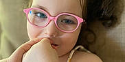 Anessia participe au concours pour gagner de l'argent avec cette photo : child, closeup, colorful, couch, curly_hair, dress, eyewear, face, glasses, hand, happy, indoor, pattern, person, pink_glasses, portrait, red_hair_accessory, skin, smiling, young