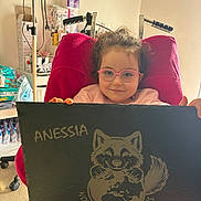Anessia a rejoint le concours — aidez-le/la à gagner de superbes lots ! black_slate, child, diapers, earth, floor, furniture, glasses, head, holding, illustration, indoor, light, medical_supplies, person, pink_sweater, raccoon, red_chair, smile, sneakers, young