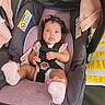 baby, infant, child, car_seat, harness, portrait, sitting, wide_eyed, curly_hair, pink_blanket, pink_clothing, socks, secure, indoor, vehicle, seat, baby_carrier, photography, face, adorable