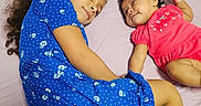 Hanah is registered to the contest to win money with this photo: children, siblings, baby, toddler, girl, infant, sister, bed, bedroom, lying_down, smiling, portrait, floral_dress, blue_dress, pink_outfit, curly_hair, long_hair, family, indoor, happy