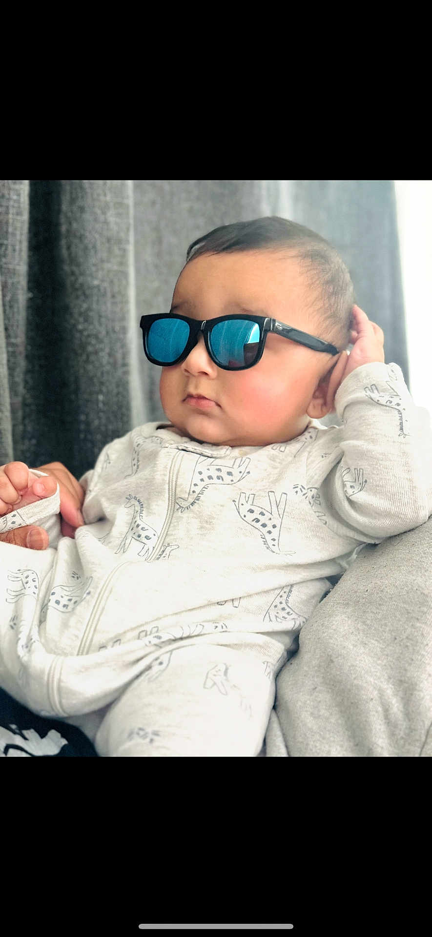 Siraj is registered to the contest to win money with this photo: baby, casual, child, closeup, cozy, cute, face, fashion, giraffe_pattern, hand, indoor, infant, onesie, person, portrait, reflection, relaxing, soft_lighting, sunglasses, young_child