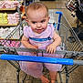 toddler, child, shopping_cart, store, clothing, shelves, dress, purple, smile, happy, indoors, floor, baby, person, retail, shopping, seatbelt, playful, cute, grocery