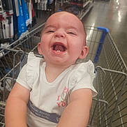 Brynleigh is registered to the contest to win money with this photo: aisle, baby, child, cute, happy, indoor, infant, laughing, person, products, retail, ruffled_sleeves, safety_belt, seat, shelves, shopping_cart, smiling, store, toddler, white_clothing