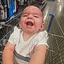 baby, shopping_cart, store, aisle, smiling, child, white_clothing, safety_belt, ruffled_sleeves, happy, indoor, retail, products, shelves, infant, person, cute, laughing, toddler, seat
