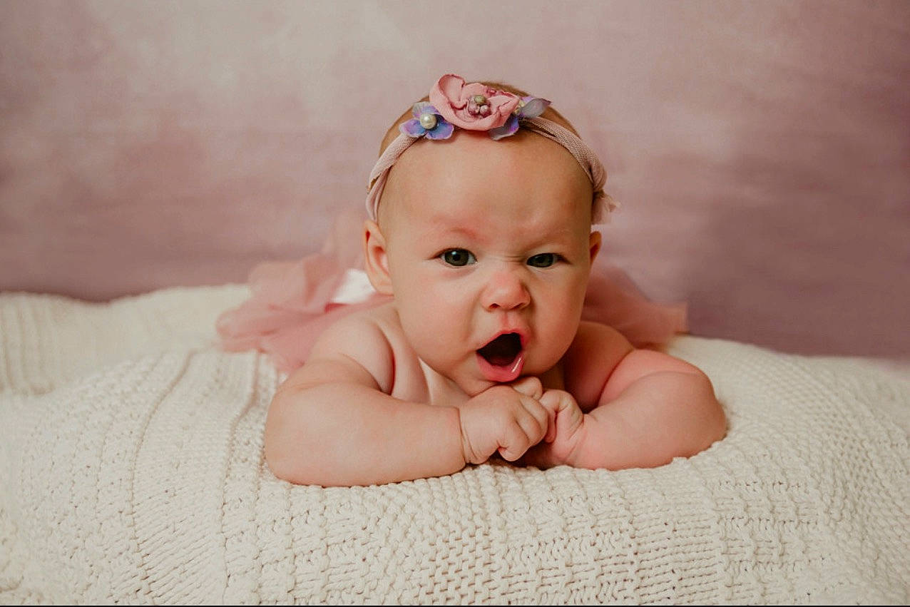 Lila joined the competition — help win amazing prizes! baby, baby_toddler_clothing, cheek, comfort, dress, eye, flash_photography, grass, hand, happy, head, headband, headgear, headpiece, iris, linens, lip, person, toddler, tummy_time