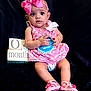 baby, child, girl, pink, dress, headband, bow, polka_dot, sitting, couch, blocks, age_marker, shoes, footwear, indoor, portrait, holding, cute, milestone, infant