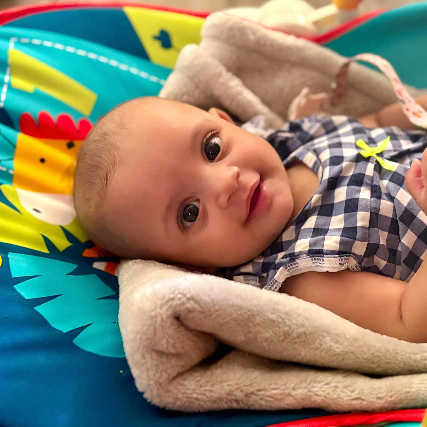 Ashley Saraev is registered to the contest to win money with this photo: baby, blanket, bright, child, clothing, colorful, cozy, cute, eyes, face, happy, indoors, infant, person, play_mat, portrait, resting, smiling, soft_texture, young