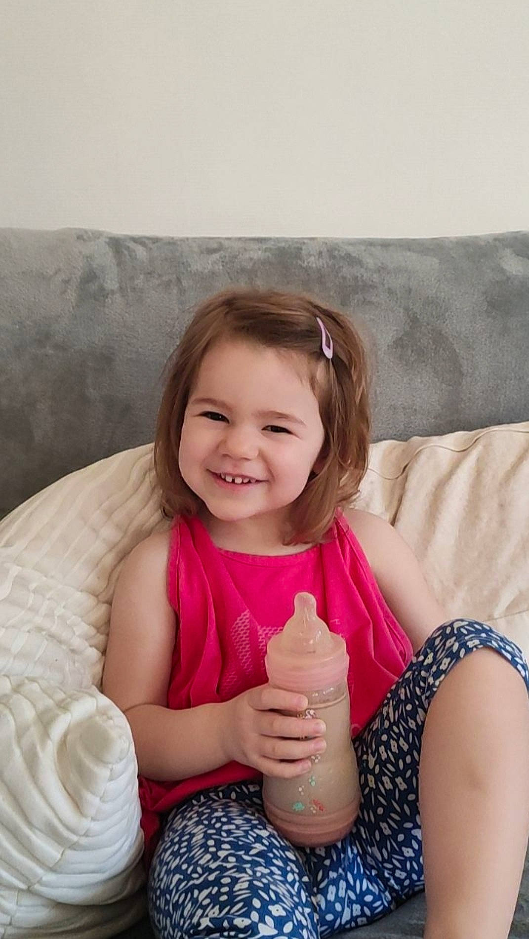 Angéline participe au concours pour gagner de l'argent avec cette photo : baby_toddler_clothing, bottle, child, comfort, dress, facial_expression, flash_photography, hairstyle, hand, happy, iris, joy, neck, person, pink, plastic_bottle, product, shoulder, skin, smile