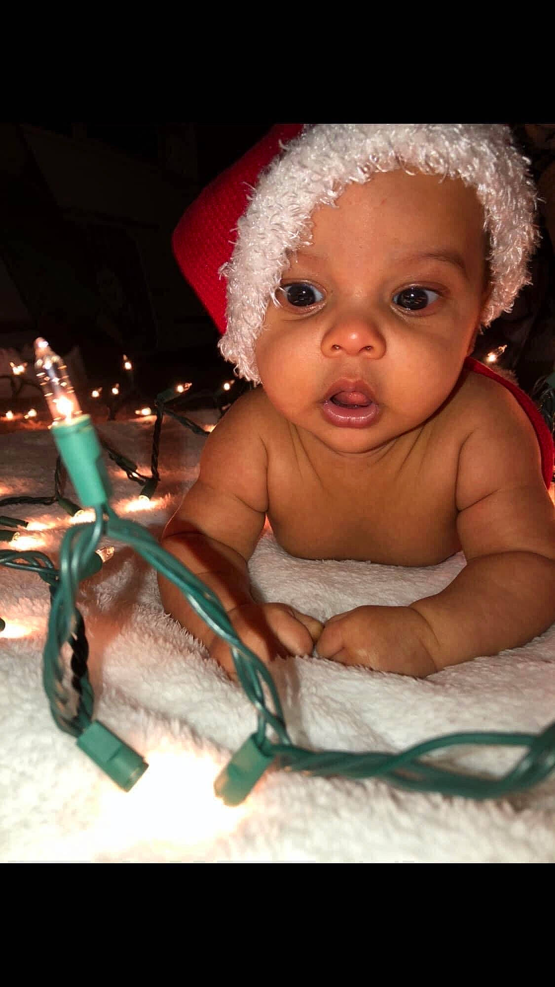 King is registered to the contest to win money with this photo: baby, baby_toddler_clothing, cheek, child, costume_hat, darkness, event, fashion_accessory, finger, flash_photography, fun, happy, iris, jewellery, lip, nose, person, sitting, skin, snapshot