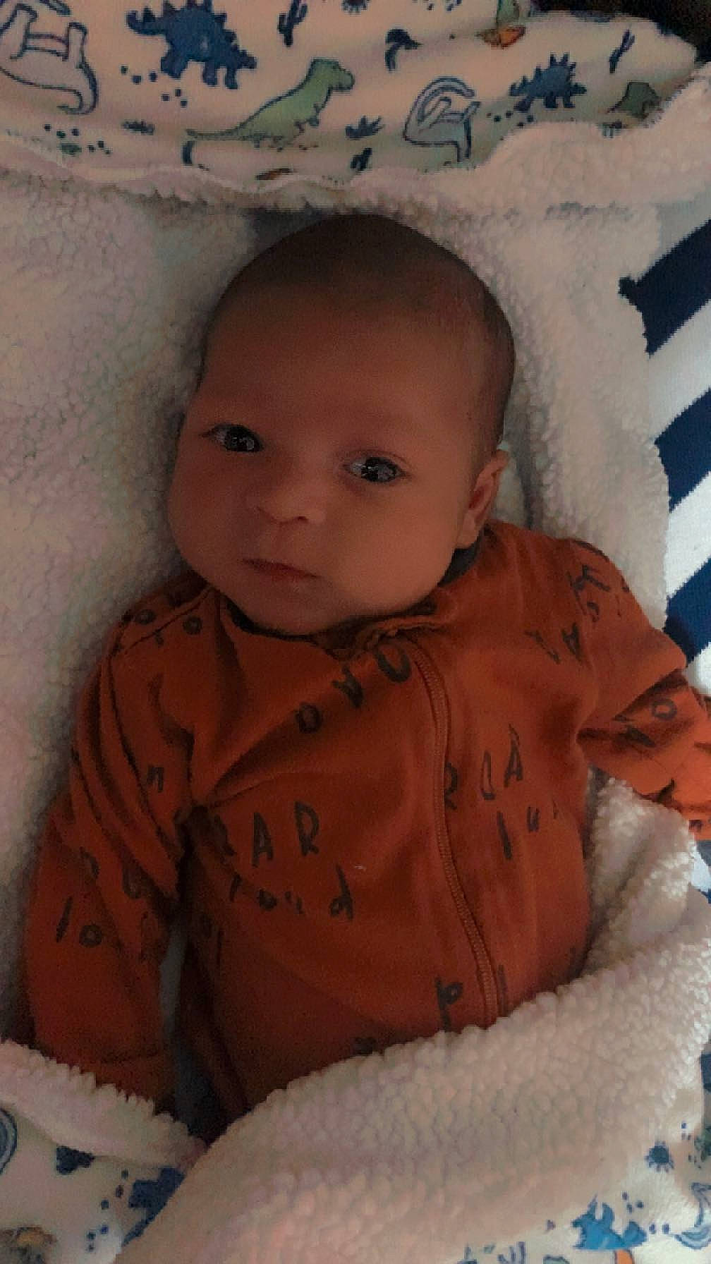 Dimitry is registered to the contest to win money with this photo: arm, baby, baby_toddler_clothing, cheek, child, chin, comfort, eyebrow, iris, linens, lip, mouth, nose, organ, pattern, person, sitting, skin, sleeve, textile