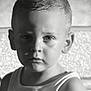 black_and_white, boy, child, close_up, dramatic_lighting, expression, face, gaze, head_and_shoulders, indoors, light, monochrome, person, portrait, serious, shadow, short_hair, studio, tank_top, young