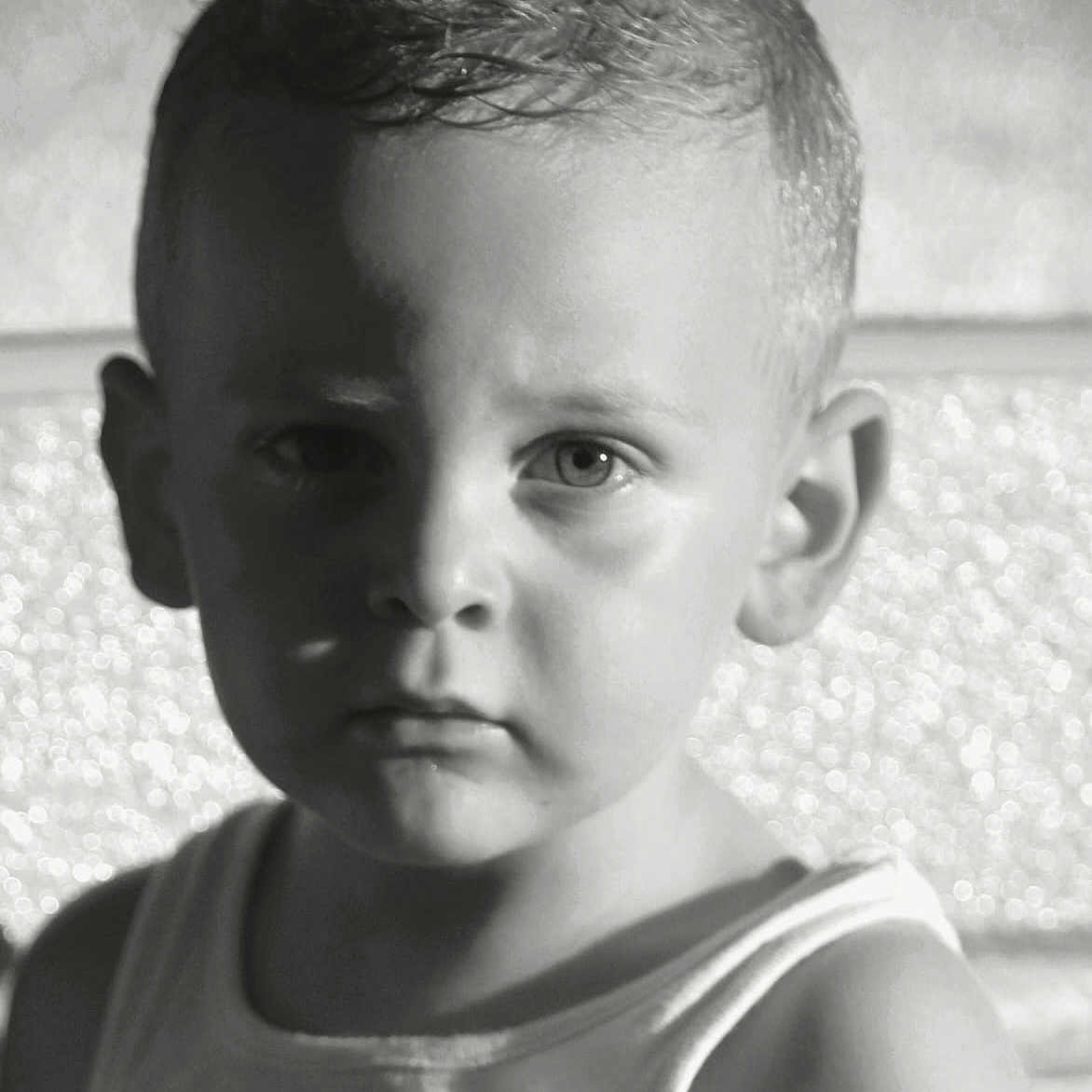 Pierre participe au concours pour gagner de l'argent avec cette photo : black_and_white, boy, child, close_up, dramatic_lighting, expression, face, gaze, head_and_shoulders, indoors, light, monochrome, person, portrait, serious, shadow, short_hair, studio, tank_top, young