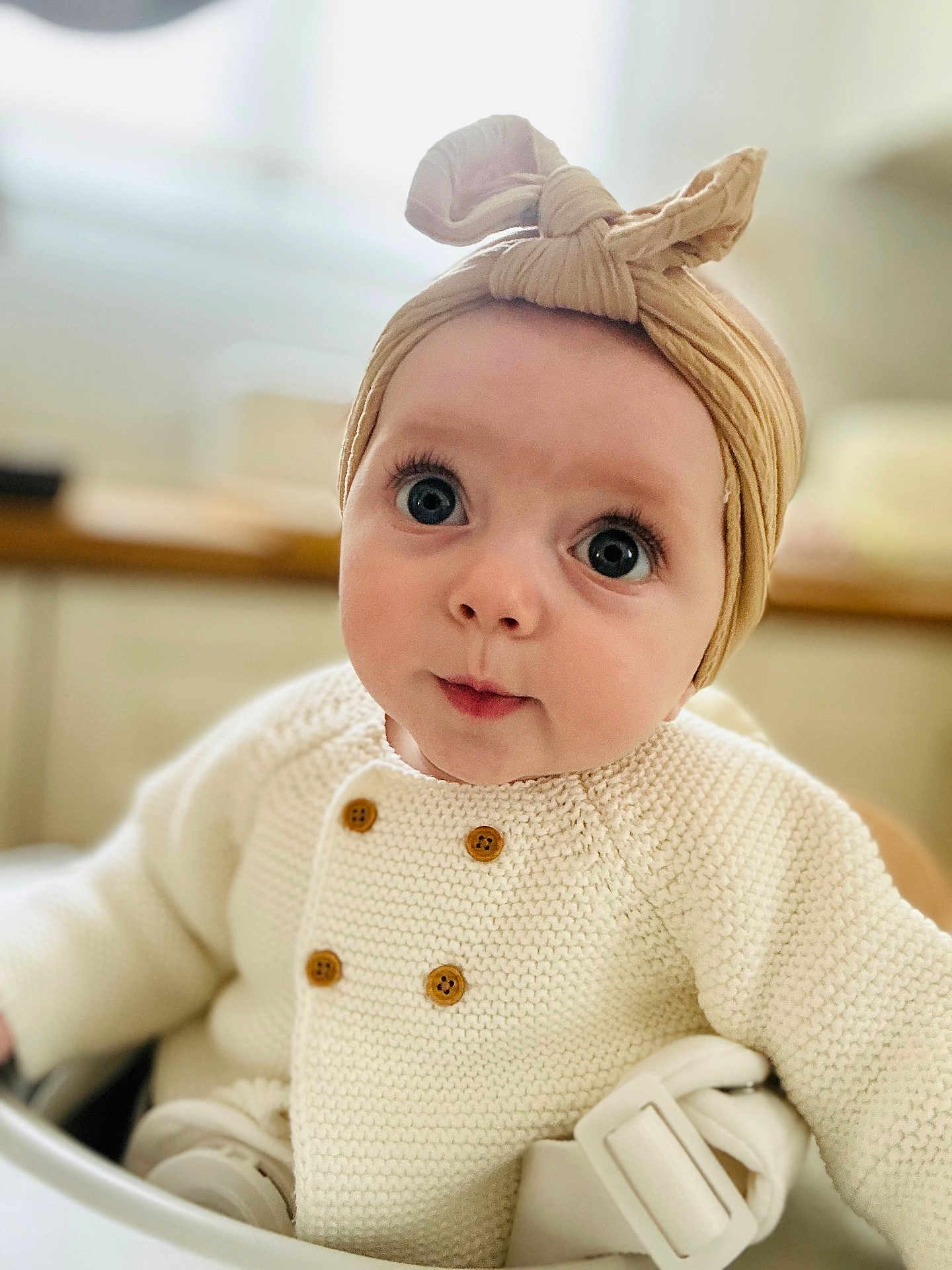 Victoire participe au concours pour gagner de l'argent avec cette photo : baby, child, face, headwrap, knit_sweater, button, high_chair, indoor, closeup, expression, curious, person, infant, seated, cute, warm_lighting, soft_focus, skin, eyes, mouth
