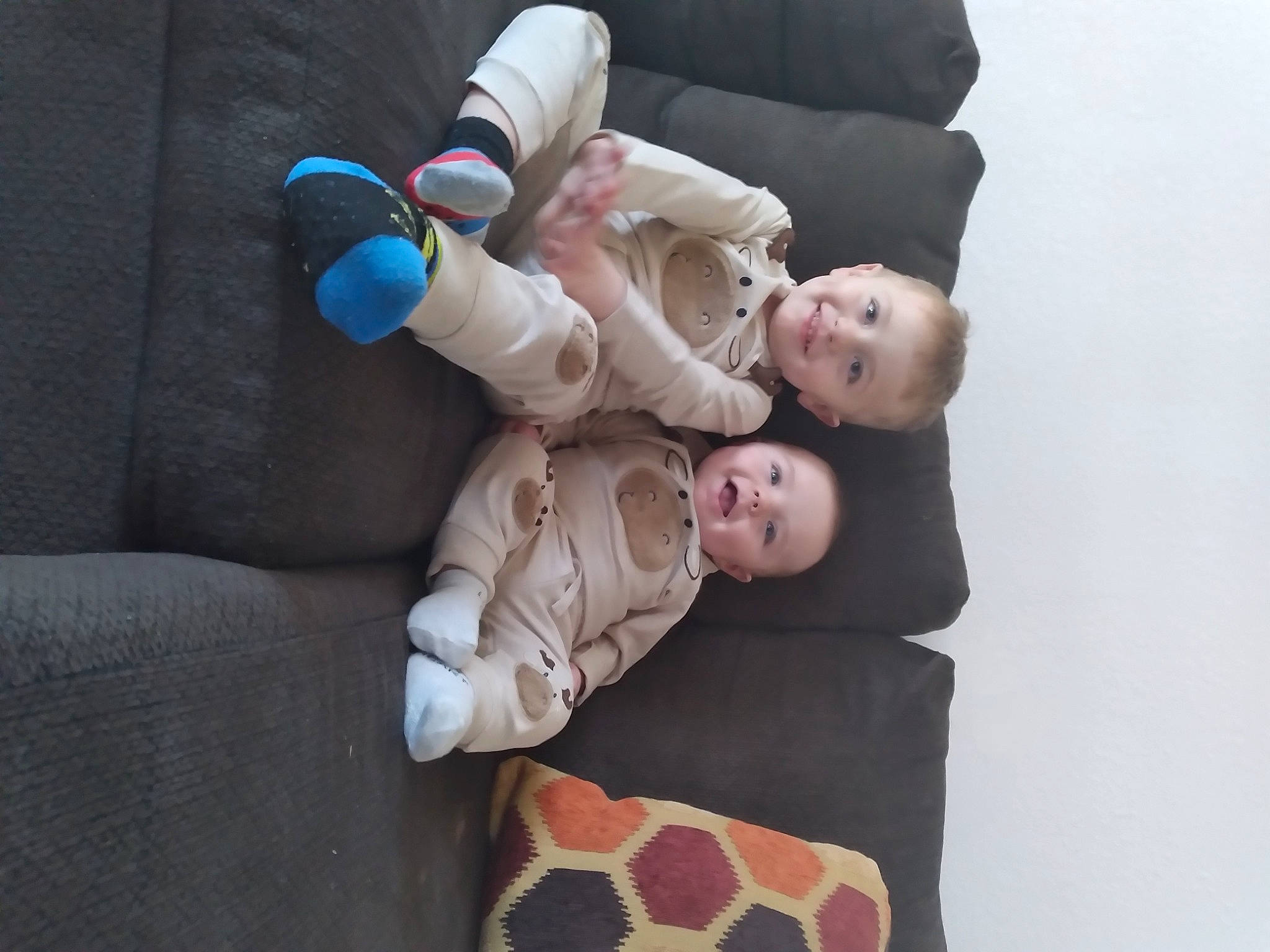 Kyle is registered to the contest to win money with this photo: arm, baby, baby_products, baby_toddler_clothing, child, comfort, couch, foot, gesture, hand, happy, human_leg, joy, knee, leg, linens, person, sitting, sleeve, smile