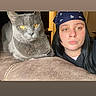 cat, person, portrait, indoor, couch, gray_cat, golden_eyes, bandana, black_hair, face, animal, pet, home, furniture, sitting, closeup, selfie, serious_expression, whiskers, photography