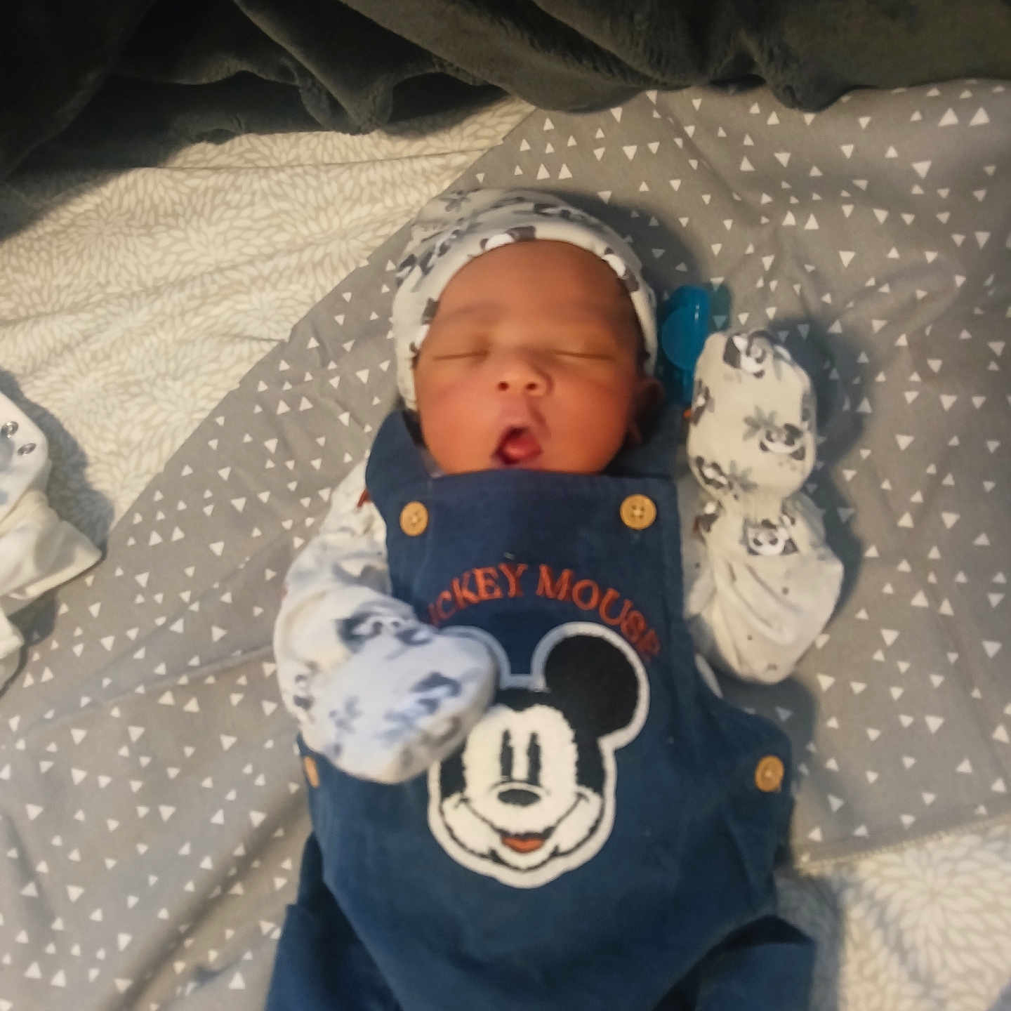 Amir is registered to the contest to win money with this photo: baby, baby_clothes, blanket, child, clothing, cozy, cute, hat, indoor, infant, lying_down, mickey_mouse, mittens, newborn, overalls, patterned_blanket, portrait, resting, sleeping, soft