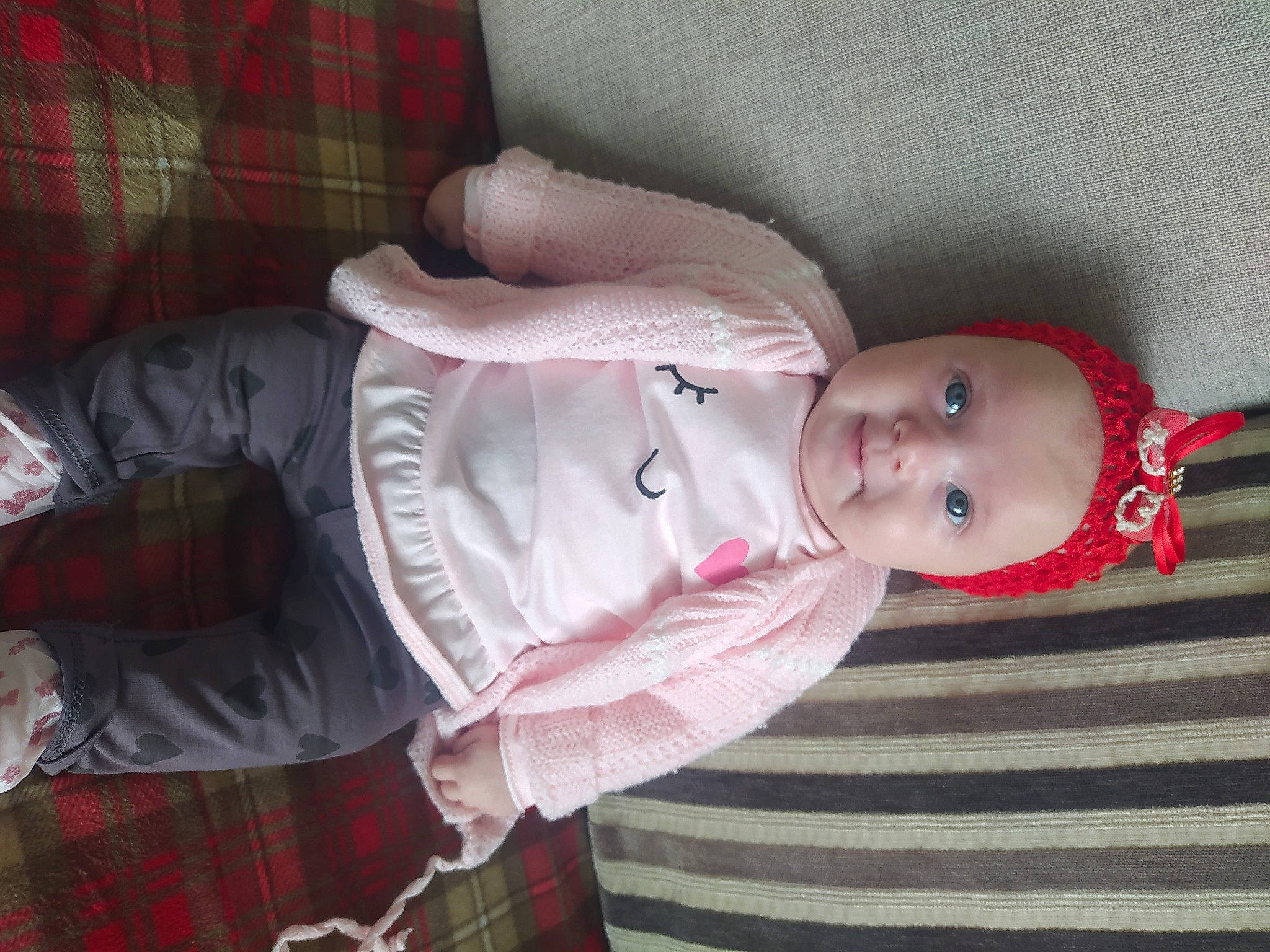 Maëlya participe au concours pour gagner de l'argent avec cette photo : arm, baby, baby_products, baby_toddler_clothing, carmine, child, comfort, flesh, hat, head, headwear, magenta, pattern, person, pink, plaid, red, skin, sleeve, tartan