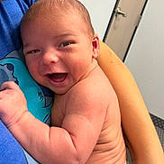 Wayne joined the competition — help win amazing prizes! baby, smiling, infant, child, person, skin, arm, hand, face, expression, happy, holding, blue_shirt, indoor, door, wrinkles, newborn, closeup, parent, comfort