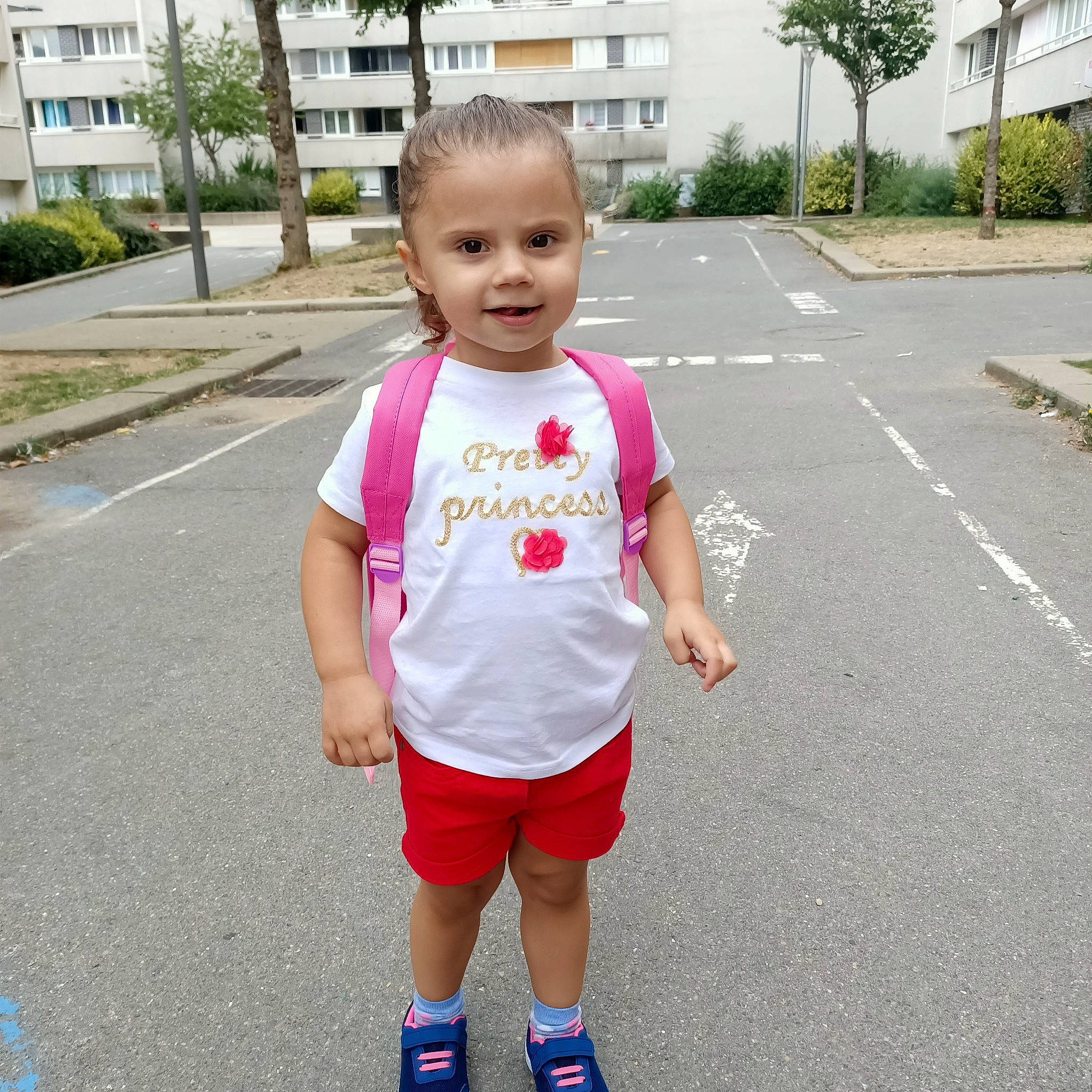 Mariana participe au concours pour gagner de l'argent avec cette photo : active_shorts, asphalt, baby_toddler_clothing, blue, fun, grass, happy, joy, leg, leisure, person, pink, plant, recreation, shorts, sleeve, smile, t_shirt, toddler, tree