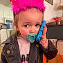 toddler, child, pacifier, toy_phone, pink_crown, leather_jacket, bracelet, indoor, portrait, cute, serious, birthday, accessory, person, clothing, face, hand, young_child, living_room, decor