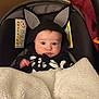 Wayland is registered to the contest to win money with this photo: baby, infant, car_seat, blanket, costume, halloween, skeleton, bat_ears, cute, face, clothing, indoors, child, person, expression, drool, soft_texture, blanket_fabric, seat, warning_label