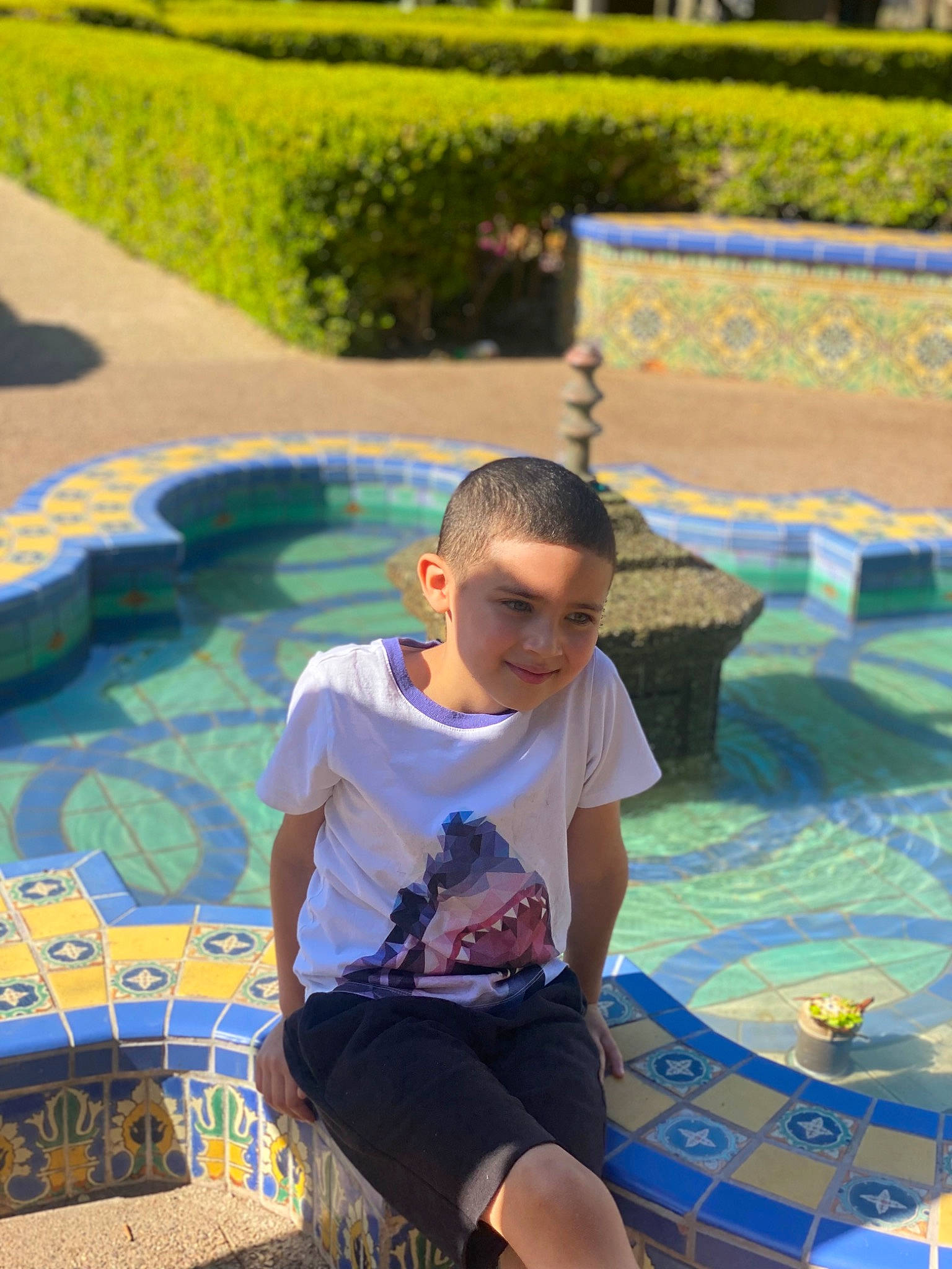 Antonio is registered to the contest to win money with this photo: child, event, eyewear, flooring, fun, grass, happy, joy, leisure, pattern, person, plant, recreation, shorts, sitting, summer, t_shirt, thigh, vacation, water