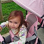 Celia a rejoint le concours — aidez-le/la à gagner de superbes lots ! canopy, child, concrete_path, face, floral_jacket, footwear, girl, grass, handlebar, outdoor, person, pink, playful, sandals, seat, smile, stroller, toy, wheel, wooden_fence