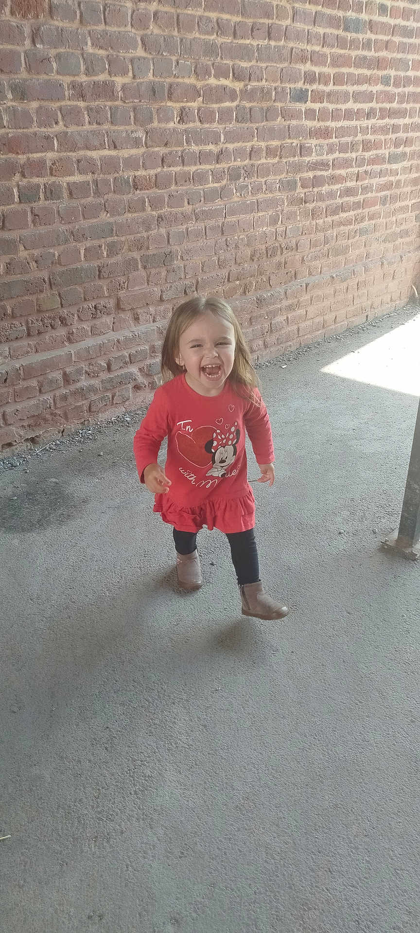 Celia a rejoint le concours — aidez-le/la à gagner de superbes lots ! boots, brick_wall, casual_clothing, child, concrete_floor, cute, daylight, full_body, happy, laughing, long_hair, minnie_mouse, outdoor, person, playful, red_dress, smiling, toddler, walking, young_girl