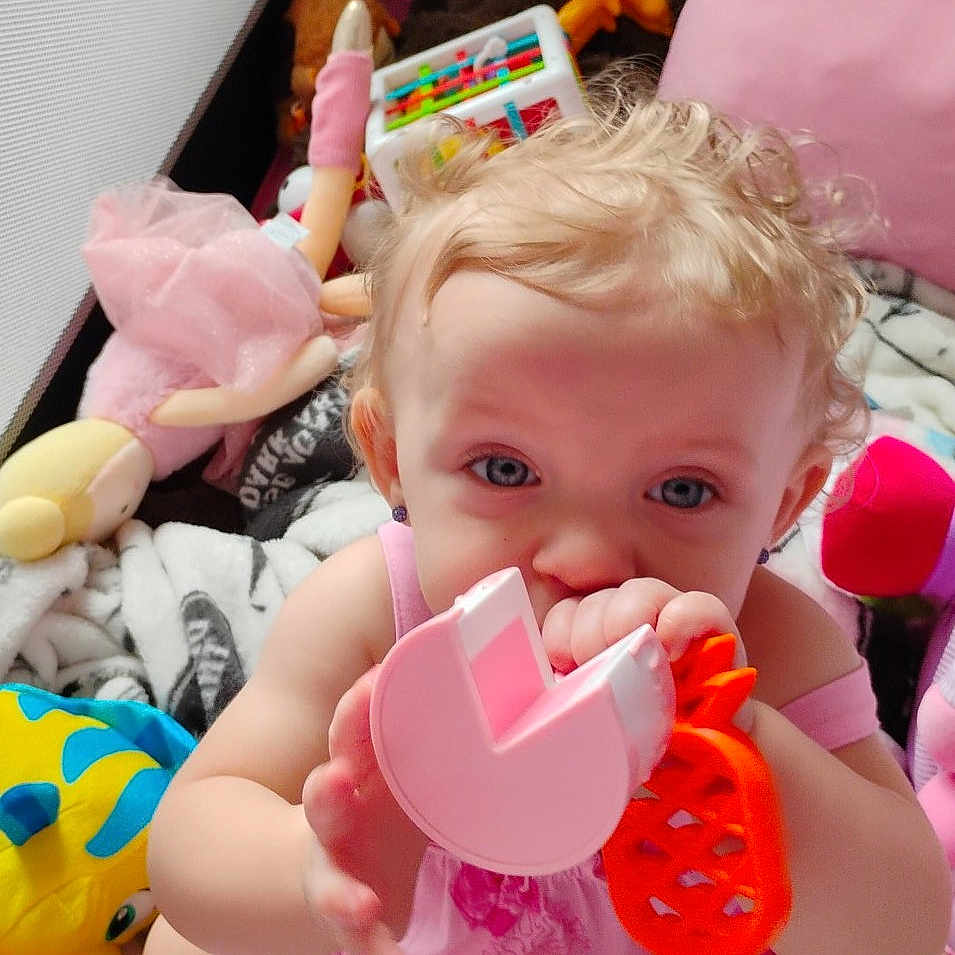 Daenerys Rhaenerya is registered to the contest to win money with this photo: baby, blanket, blue_eyes, child, closeup, colorful, curly_hair, cute, doll, fun, indoor, infant, pink_clothing, play_area, playtime, sitting, soft_toys, stuffed_animal, teether, toys