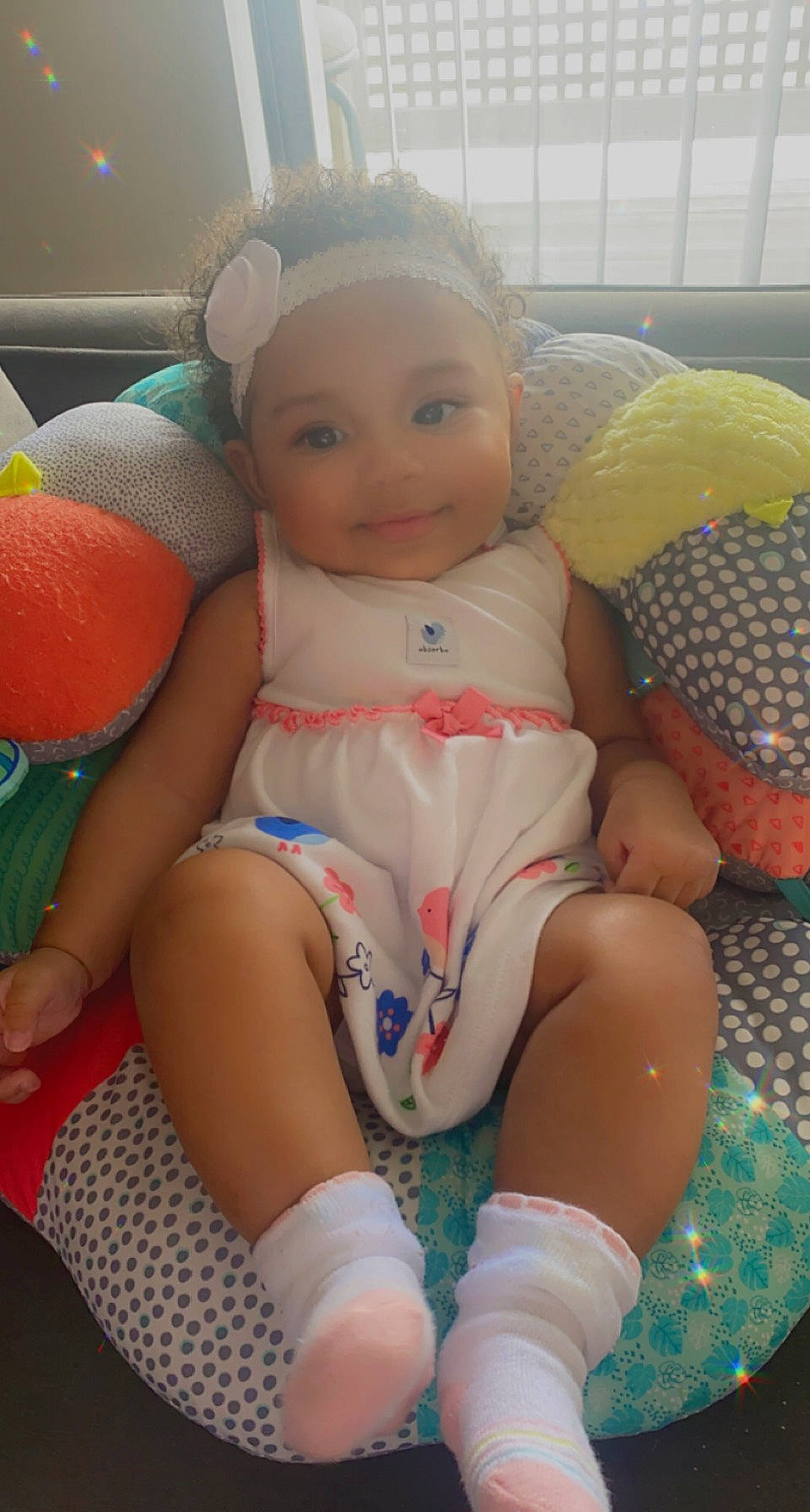 Nia is registered to the contest to win money with this photo: abdomen, baby_toddler_clothing, cheek, chest, comfort, finger, happy, head, headwear, human_body, joint, joy, knee, lap, leg, mouth, person, pink, skin, smile