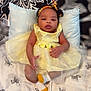 baby, yellow_dress, headband, pillow, blanket, zebra_pattern, socks, infant, cute, child, portrait, indoors, soft_lighting, smiling, resting, comfort, fabric, tulle, hand, feet