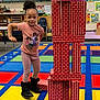 child, girl, classroom, blocks, toy, carpet, colorful, education, learning, play, building, stack, furniture, poster, boots, clothing, smile, hair, indoor, preschool