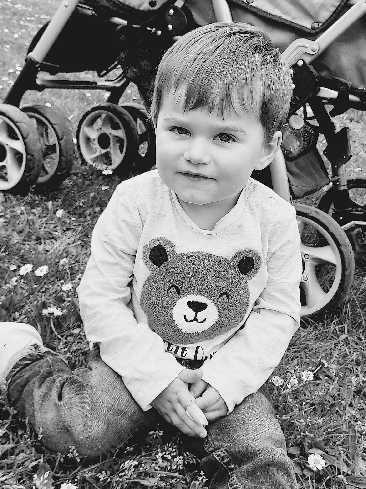 Wyatt participe au concours pour gagner de l'argent avec cette photo : automotive_tire, black, black_and_white, child, cool, fender, grass, happy, monochrome, motor_vehicle, people, person, photograph, smile, standing, style, tire, toddler, vehicle, wheel