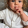 child, toddler, baby, face, hair, curly_hair, onesie, foot, hand, fingers, indoor, couch, blanket, clothing, cute, portrait, sitting, expression, skin, infant