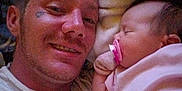 Raven is registered to the contest to win money with this photo: man, baby, sleeping, pacifier, blanket, smile, face, portrait, indoor, closeup, cozy, tender, affection, resting, child, adult, human, head, comfort, family
