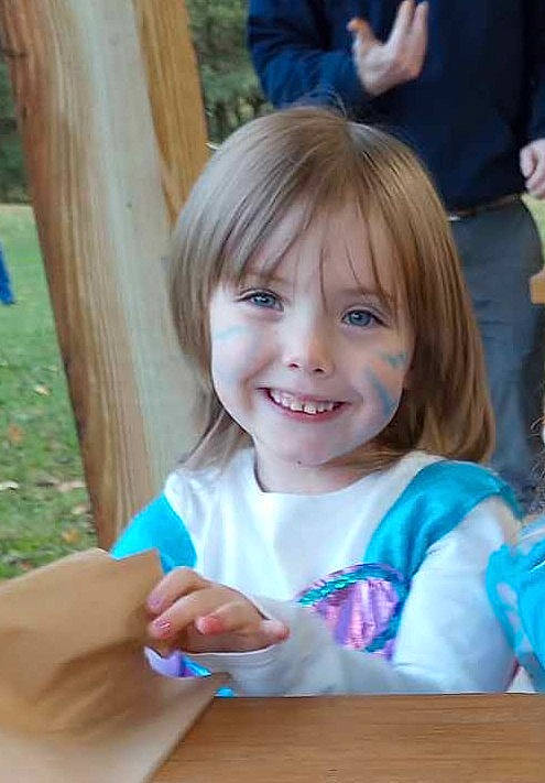 Presley is registered to the contest to win money with this photo: bangs, blond, child, event, facial_expression, finger, fun, gesture, grass, happy, joy, leisure, person, plant, recreation, smile, summer, table, thumb, toddler