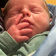 Cyrus is registered to the contest to win money with this photo: newborn, baby, infant, sleeping, face, portrait, hand, fingers, green_clothing, blanket, swaddled, held, close_up, indoors, person, skin, eyes_closed, nose, mouth, cozy