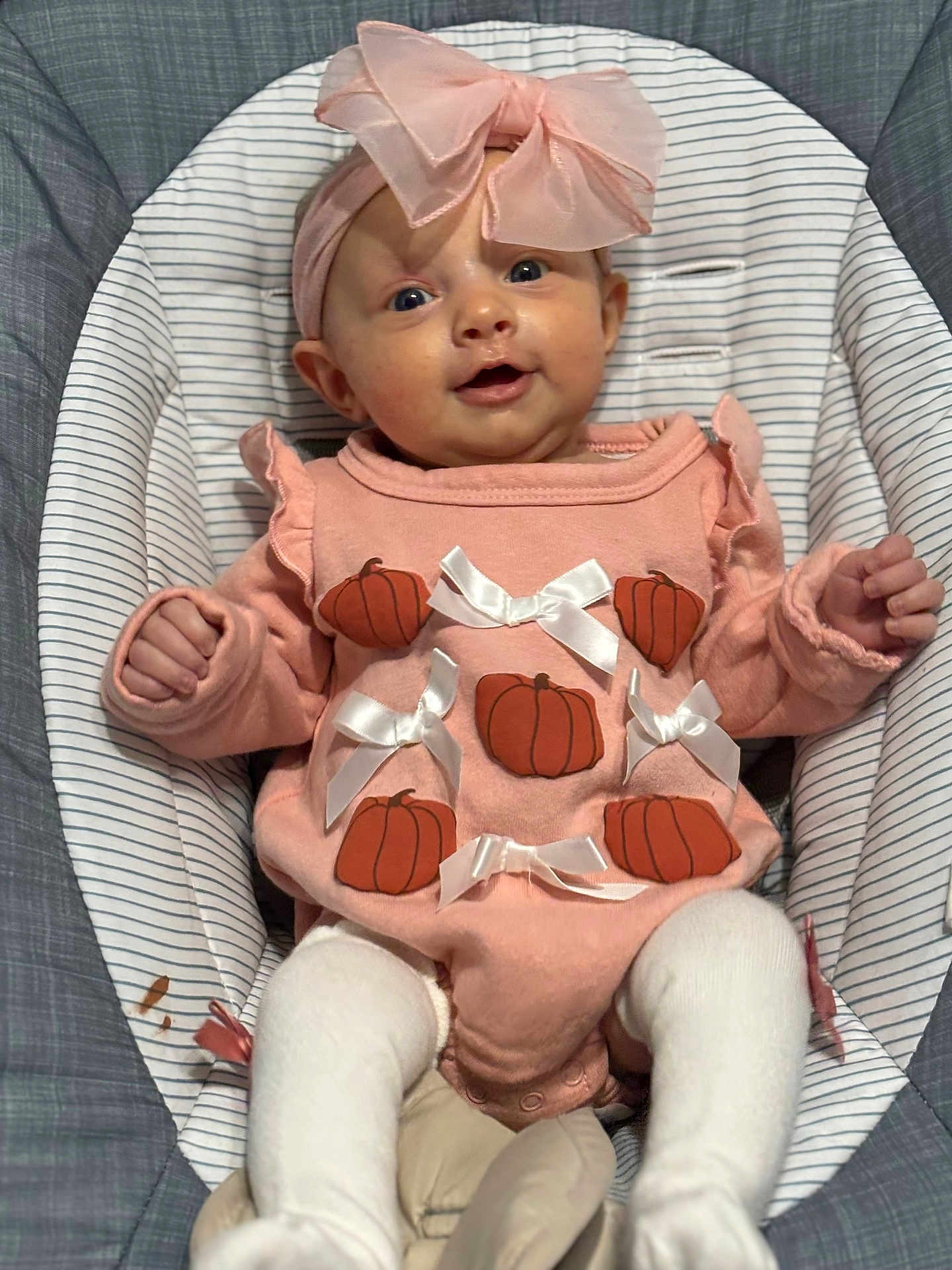 Delilah joined the competition — help win amazing prizes! baby, infant, pink_outfit, headband, bow, pumpkin, white_bows, striped_cushion, cushion, seat, smiling, happy, child, cute, clothing, portrait, indoors, legs, hands, face