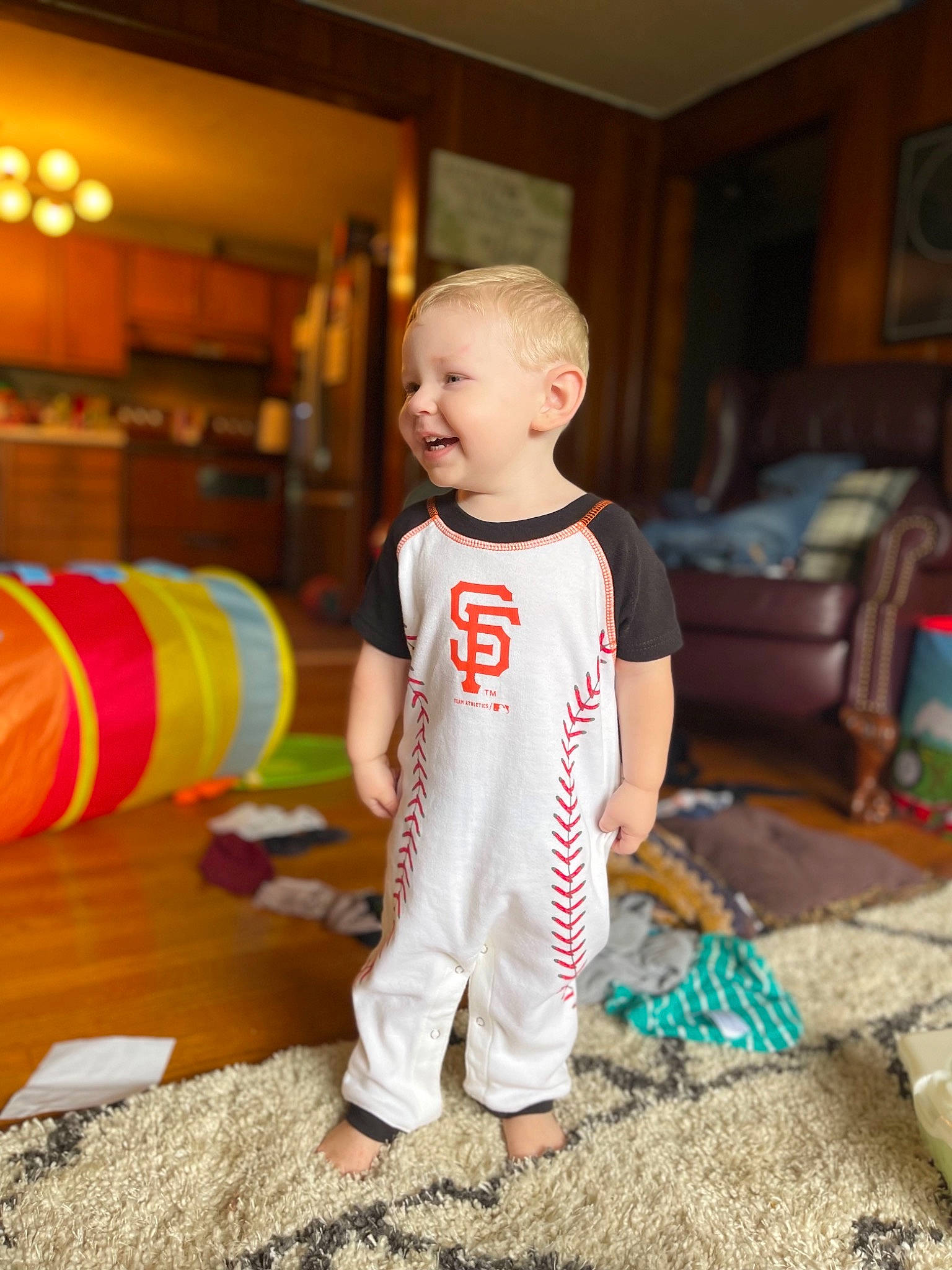 Kolten is registered to the contest to win money with this photo: baby, baby_toddler_clothing, child, couch, floor, flooring, fun, games, happy, head, joy, leisure, person, play, recreation, room, smile, standing, t_shirt, toddler