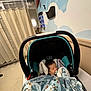 baby, blanket, car_seat, child, clinic, hospital, indoor, pacifier, person, seat, sleeping, wall_art, curtain, adult, blue, cozy, decor, infant, mural, woodland