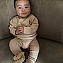 baby, infant, child, face, hands, pajamas, slippers, couch, furniture, seated, indoors, cute, smiling, cozy, soft, woolen, expression, looking_at_camera, plush, comfortable