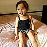 bed, bedspread, black_tank_top, casual_clothing, child, cute, face, furniture, hair, happy, home, indoor, legs, leopard_print_shorts, light, person, sitting, smiling, toddler, young_child