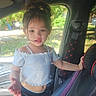 toddler, child, car, seat, window, sunlight, hair, casual_clothing, curious, standing, interior, seatbelt, black_pants, white_top, messy_hair, daylight, vehicle, young_child, portrait, indoors