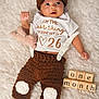 baby, infant, newborn, knit_hat, brown_hat, onesie, text_on_shirt, wooden_blocks, blocks, plush_toy, blanket, furry_blanket, crochet_pants, brown_clothing, cute, portrait, milestone, one_month, hands, face